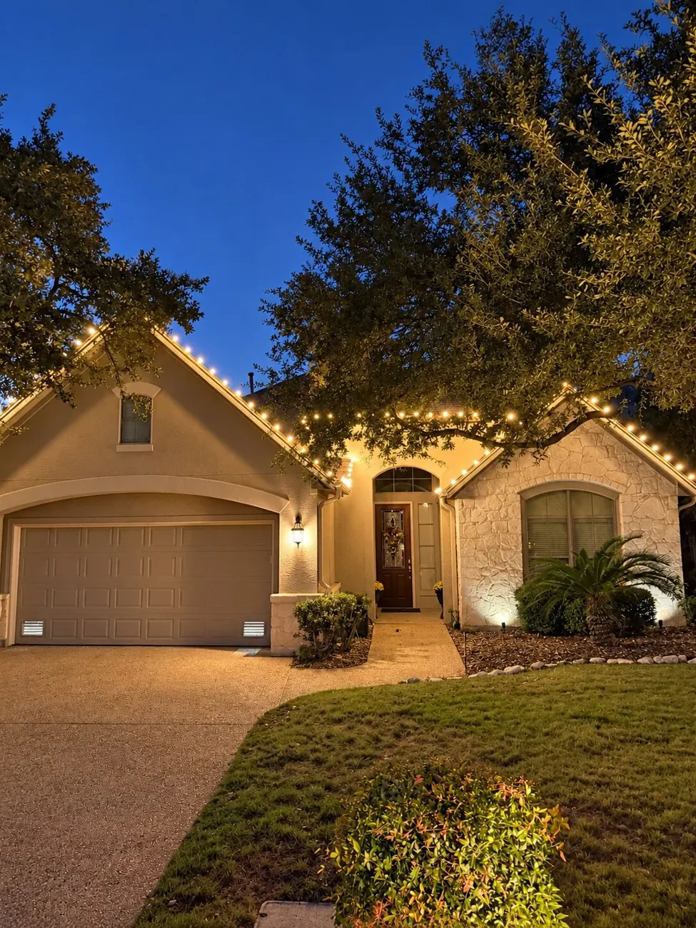 Warm Christmas lights outlining a home at twilight